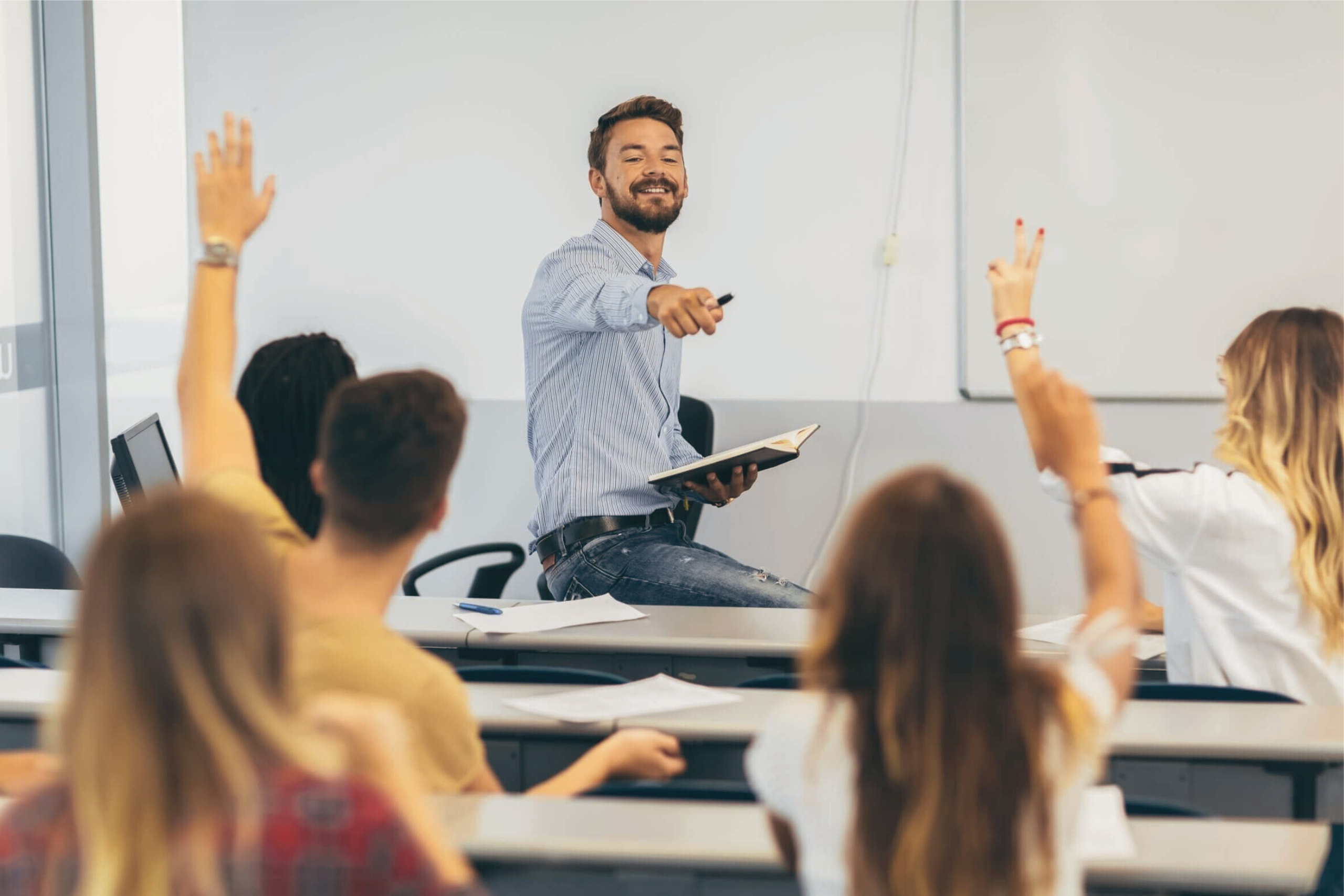 Der Lehrer unterrichtet die Schüler in Deutsch. Großes helles Klassenzimmer mit Tafel Lehrer und Schüler schreiben aktiv